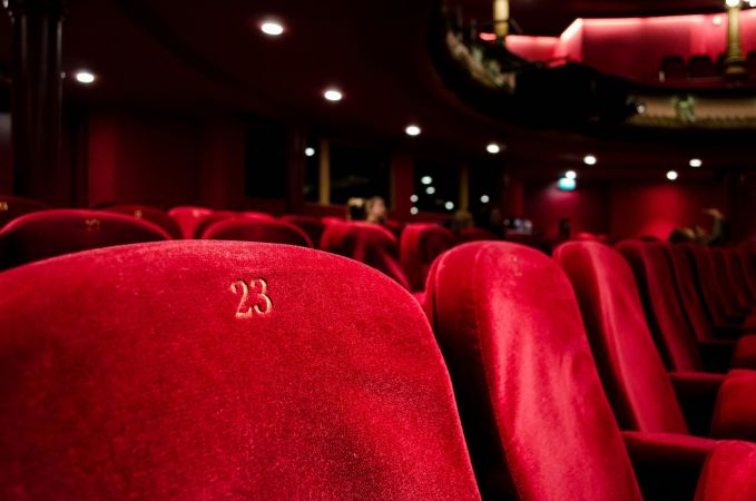 River Road Estate Red theater seats arranged in rows, complemented by a rich red curtain in the background, creating a vibrant ambiance.