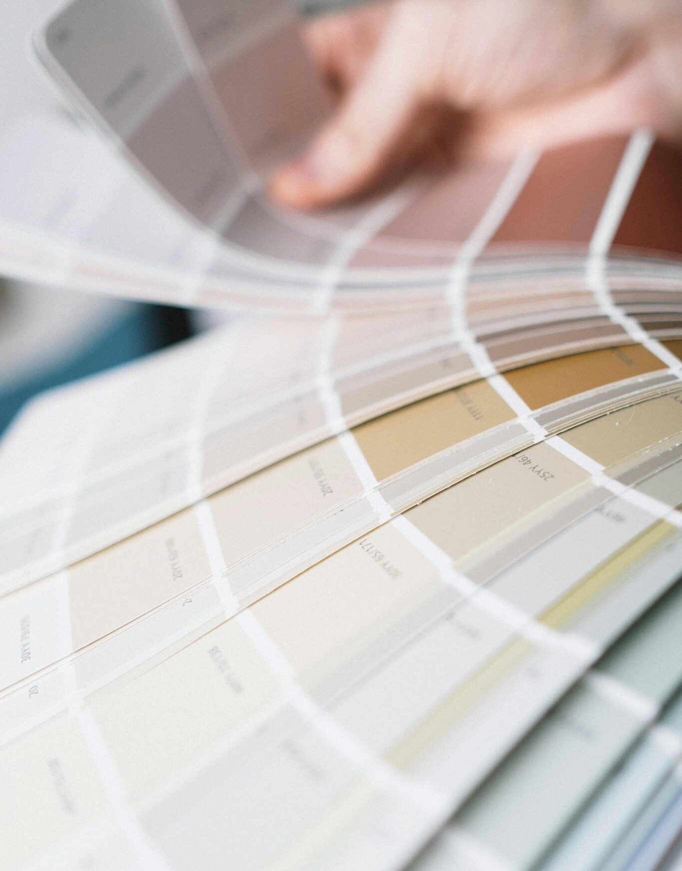 Zoomed in view of a human hand holding a paint swatch book fanned open at River Road Estates